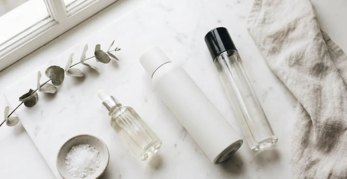 Flat lay de produits capillaires professionnels anti-humidité sérum spray laque sur surface marbre ambiance scandinave